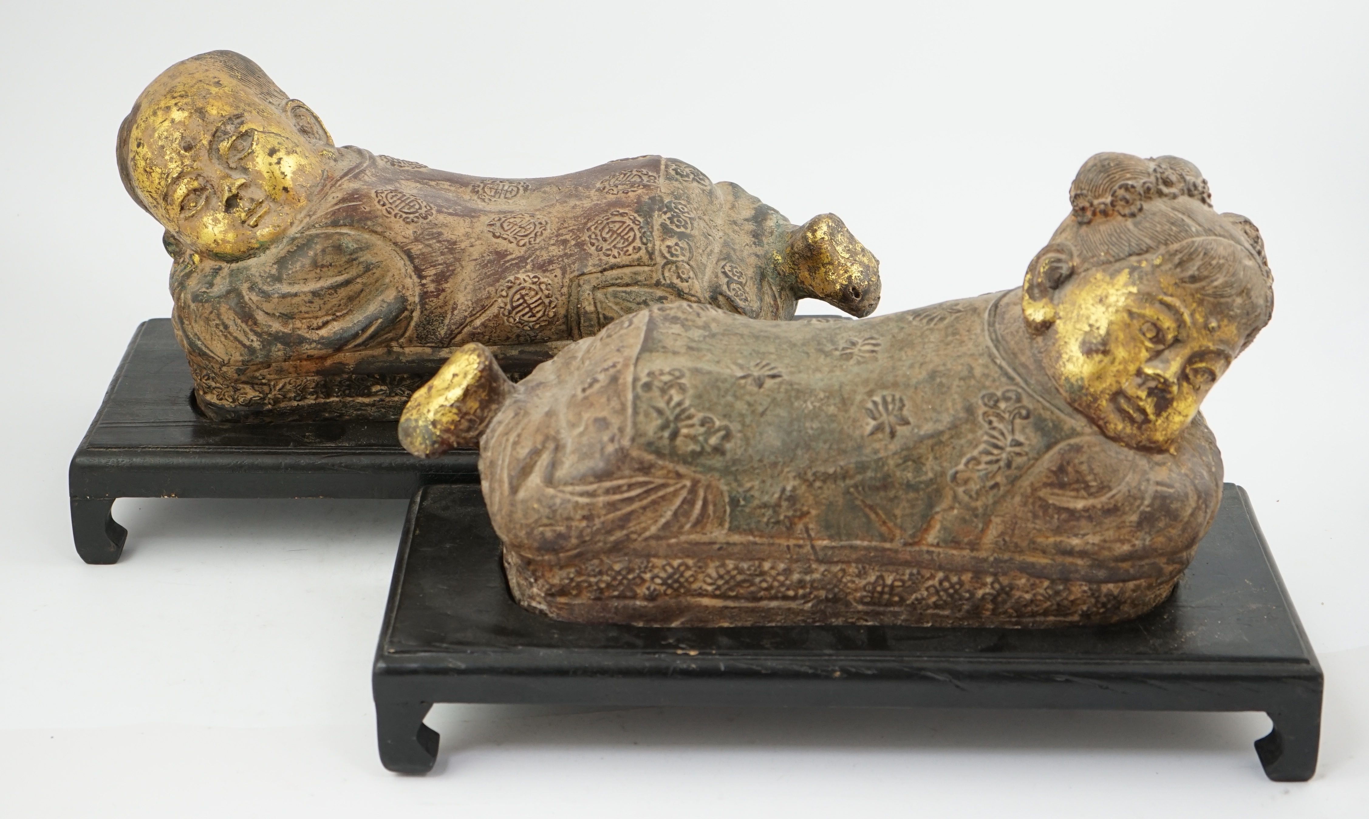 Two Chinese polychrome decorated iron pillows, modelled as sleeping children, on ebonised wood plinths, 44cm long. Condition - fair to good